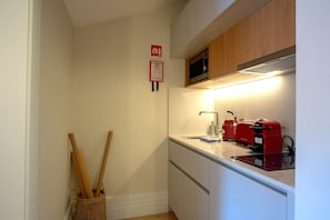 Uma cozinha compacta com micro-ondas, torradeira e pia.
