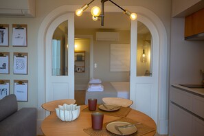 A modern hotel room with a dining area, a sofa, and a hallway leading to a bathroom. - Porto Haven - Cedofeita 213 (Porto)