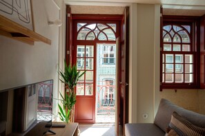 A room with a television, a plant, a sofa, and a door leading to an outdoor area with a railing. - Porto Haven - Cedofeita 213 (Porto)