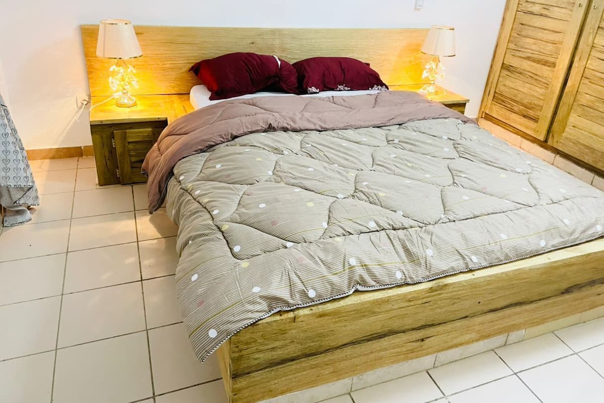 Un lit avec une tête de lit en bois, deux tables de chevet avec des lampes et une armoire.
