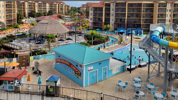 Ein Resort mit Poolbereich, einer Wasserrutsche und mehreren Hotels im Hintergrund.