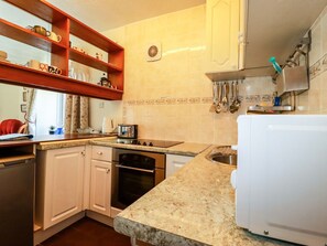 Une cuisine avec des meubles blancs, une cuisinière, un four, un évier et un plan de travail.