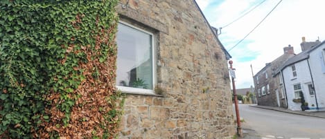 A stone building with a window and a bench outside.