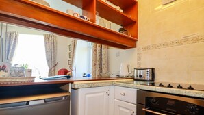 A compact kitchen with a dishwasher, oven, and a coffee maker on the counter. - Chyancrowse (Penzance)