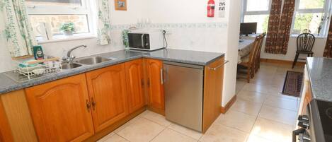 A kitchen with wooden cabinets, a built-in dishwasher, a microwave, and a sink.