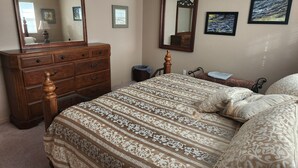 A bedroom with a large bed, a dresser, a mirror, and two framed pictures on the wall. - Sailboat waterfront home with 60 ft dock on deep canal and heated pool (Punta Gorda)