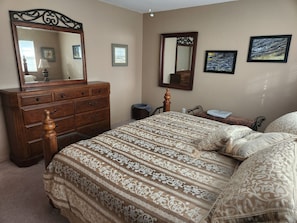 A bedroom with a large bed, a dresser, a mirror, and two framed pictures on the wall. - Sailboat waterfront home with 60 ft dock on deep canal and heated pool (Punta Gorda)