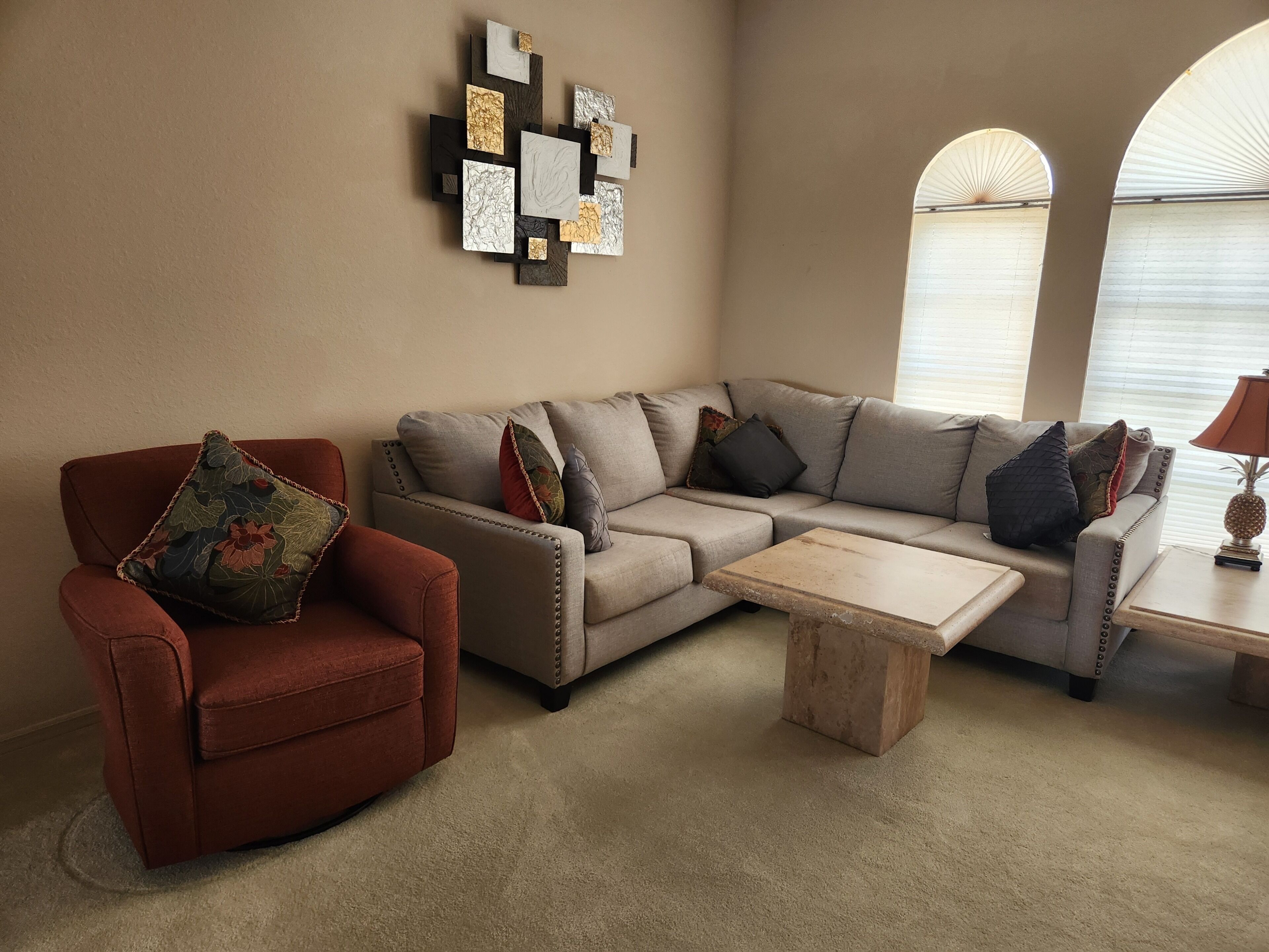 Una sala de estar con un sillón rojo, un sofá color beige y una mesa de centro.
