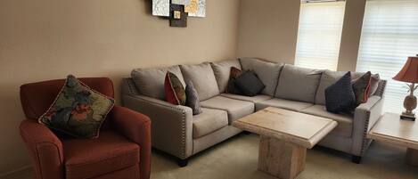 Una sala de estar con un sillón rojo, un sofá color beige y una mesa de centro.