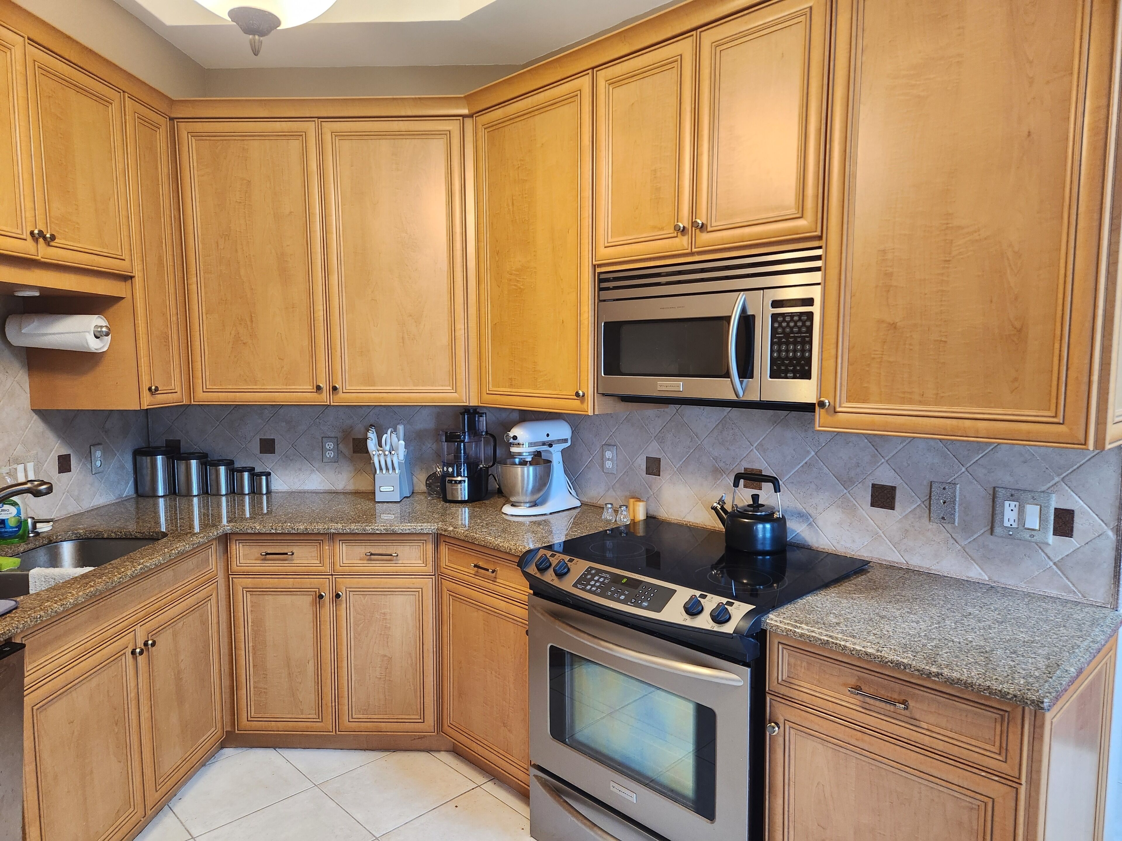 A kitchen with wooden cabinets, stainless steel appliances, a granite countertop, and a built-in oven.