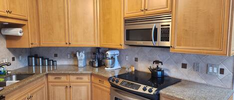 A kitchen with wooden cabinets, stainless steel appliances, a granite countertop, and a built-in oven.