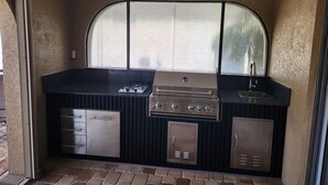 A compact kitchen with a gas stove, a sink, and storage cabinets. - Sailboat waterfront home with 60 ft dock on deep canal and heated pool (Punta Gorda)
