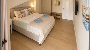 Une chambre à coucher avec un lit, des tables de chevet, une armoire, un miroir, une porte et un tableau accroché au mur.