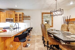 A dining area with a long wooden table, black chairs, and a chandelier. - Managed by Park City Lodging-Prime Location Steps from Skiing, Dining/Shopping (Park City)