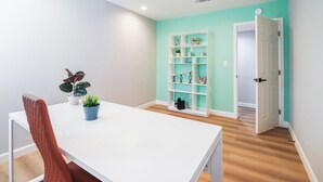 A room with a white table, a red chair, a teal wall, and a white door. - The Escape Insurance approved Single story Pool (Los Angeles)