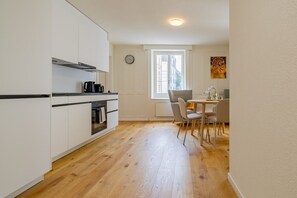 Eine kleine Küche mit weißen Schränken, einem Backofen und einer Kaffeemaschine.
