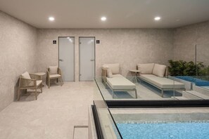 A modern indoor pool area with lounge chairs, a glass-enclosed pool, and a tiled wall. - Refined Spacious Studio, Balcony, Pool & Gym (Mexico City)
