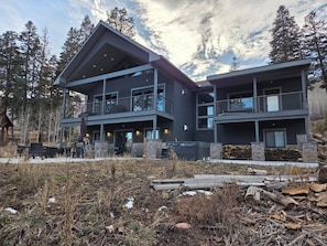 Et moderne hus med to etager, en balkon, en stensokkel og udsigt til den omkringliggende skov.
