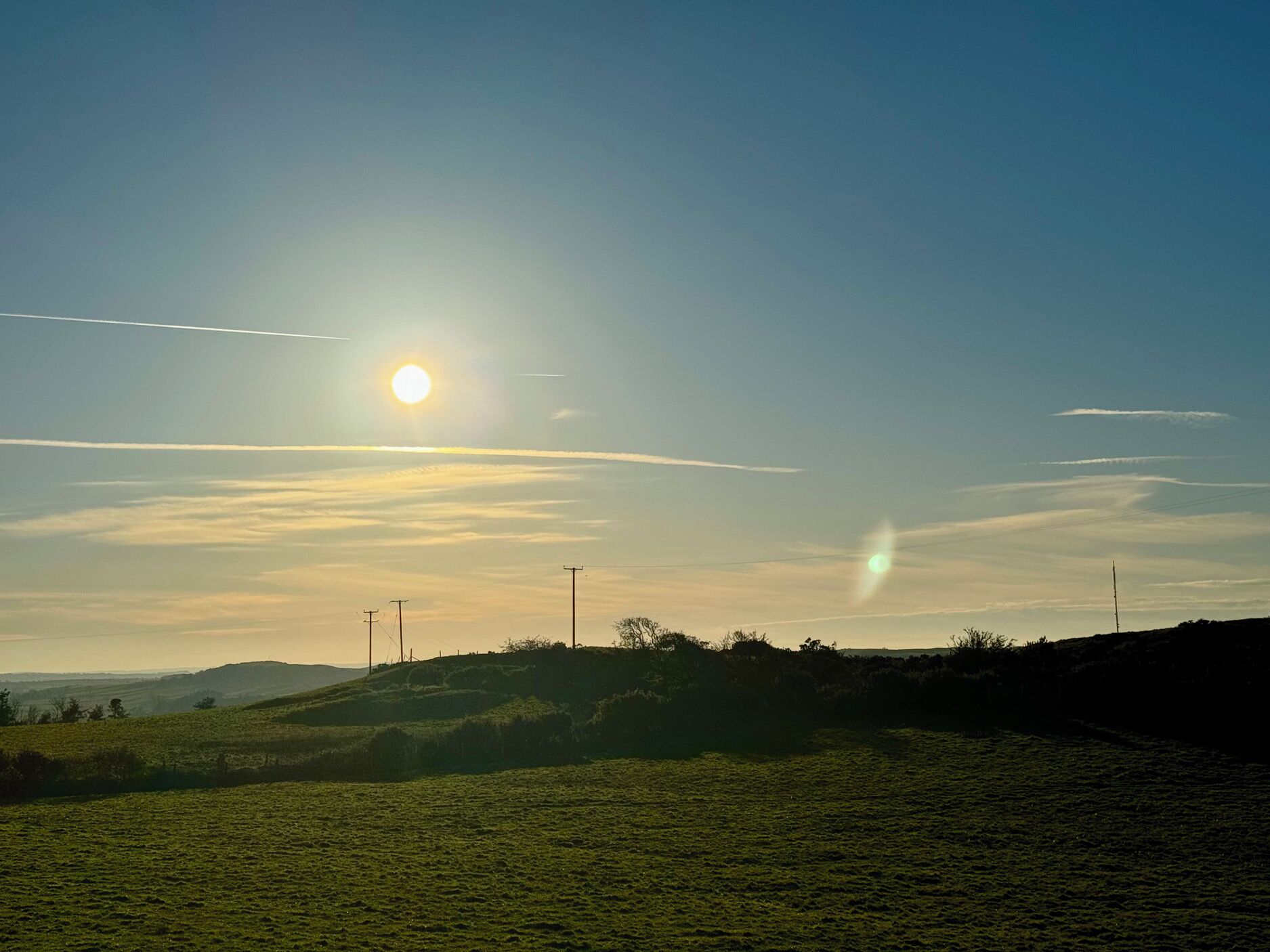 A grassy field with a clear sky and distant hills.