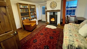 Una sala de estar acogedora con chimenea, una estantería, un sillón de cuero y una alfombra estampada.