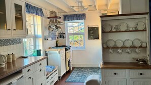 Una cocina con armarios blancos, un menú en pizarra y un ventanal con vistas.