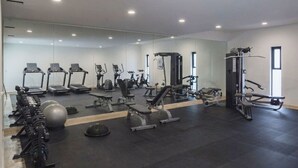 Une salle de sport équipée de tapis de course, d’appareils de musculation et de ballons d’exercice.