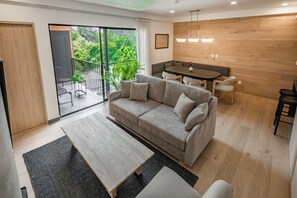 A modern living room with a sofa, a dining table, and a balcony with outdoor furniture. - Radiant 2BR 2BA, Pool, Gym & Roof Garden (Mexico City)