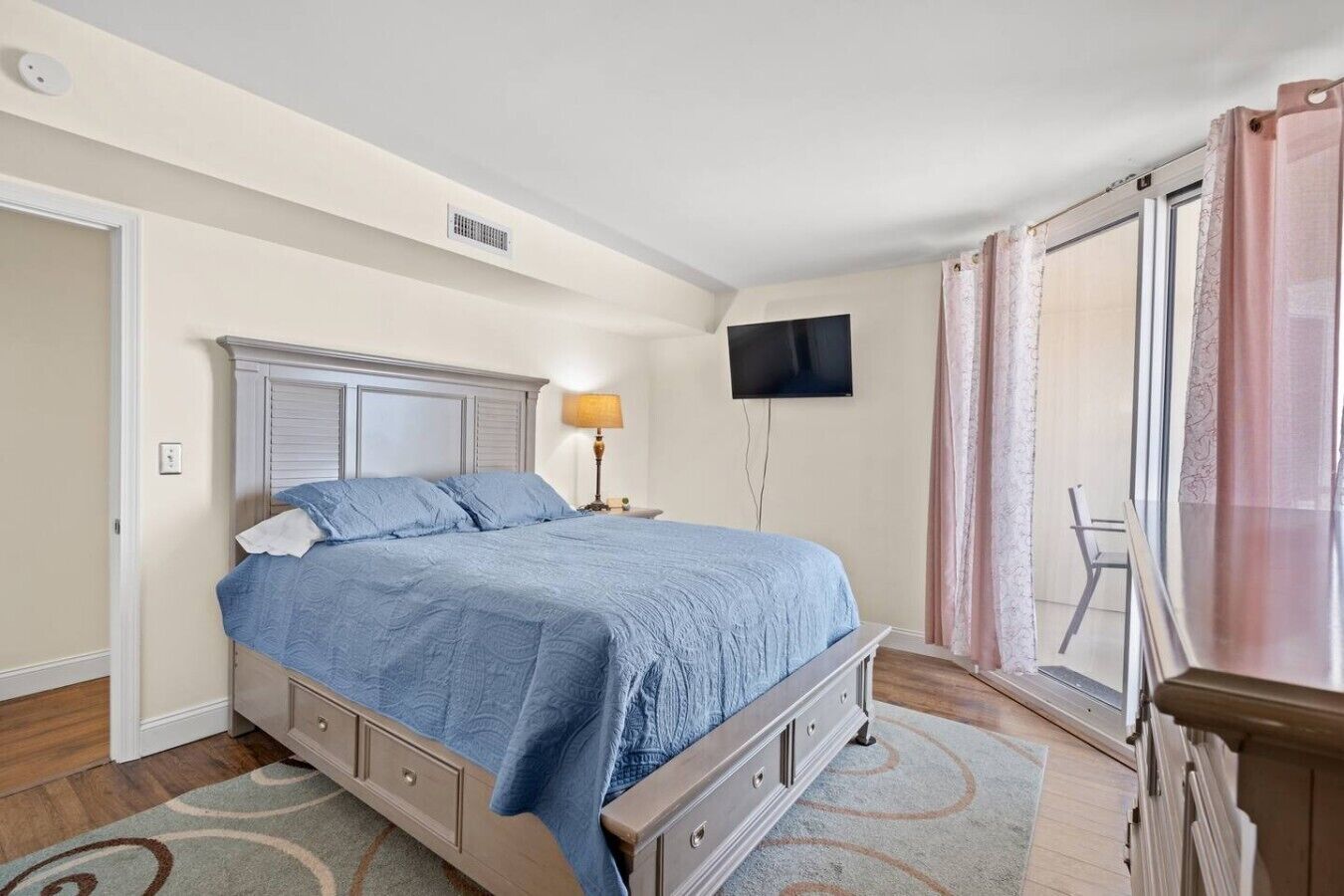 Une chambre avec un lit, une télévision, une fenêtre avec des rideaux et une chaise.