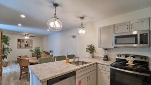 Eine moderne Küche mit Granit Arbeitsplatten, Edelstahlgeräten und Pendelleuchten.