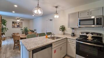 A modern kitchen with granite countertops, stainless steel appliances, and pendant lighting.