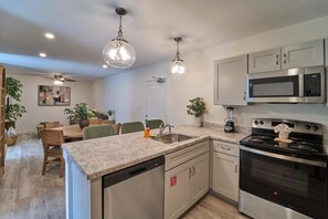 A modern kitchen with granite countertops, stainless steel appliances, and pendant lighting. - The Ruby 100 (Pigeon Forge)