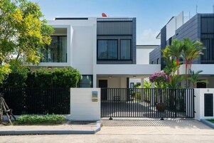 A modern two-story building with a gated entrance, large windows, and a satellite dish.