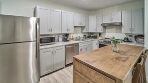 A modern kitchen with stainless steel appliances, white cabinets, and a wooden island. - The Ruby 102 (Pigeon Forge)
