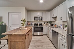 A modern kitchen with white cabinets, a wooden island, stainless steel appliances, and a green appliance in the corner. - The Ruby 103 (Pigeon Forge)