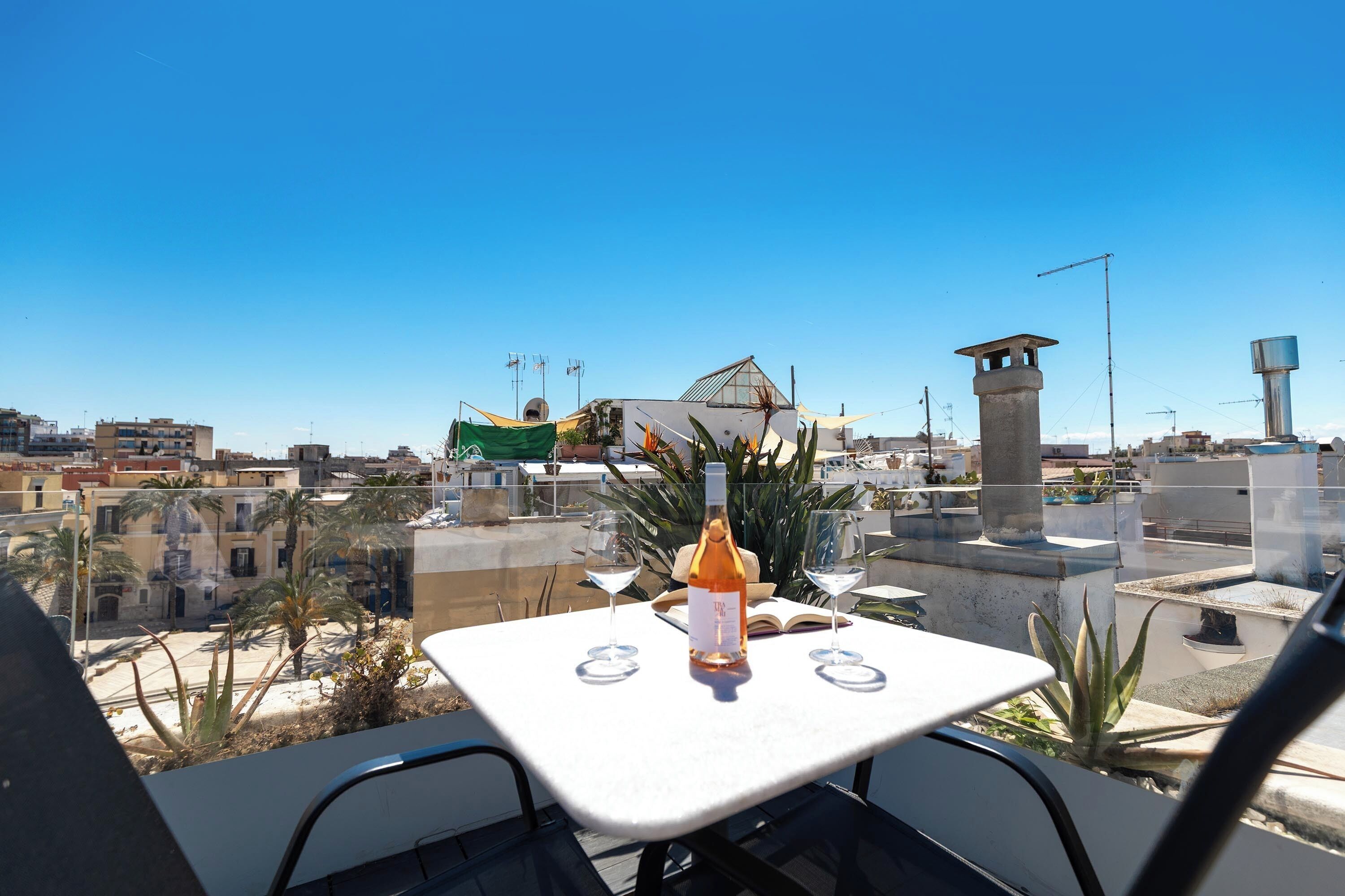 A rooftop terrace with a table set for two, overlooking a cityscape.