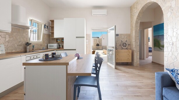 Una cocina moderna con comedor, paredes de piedra y vistas a través de un ventanal.