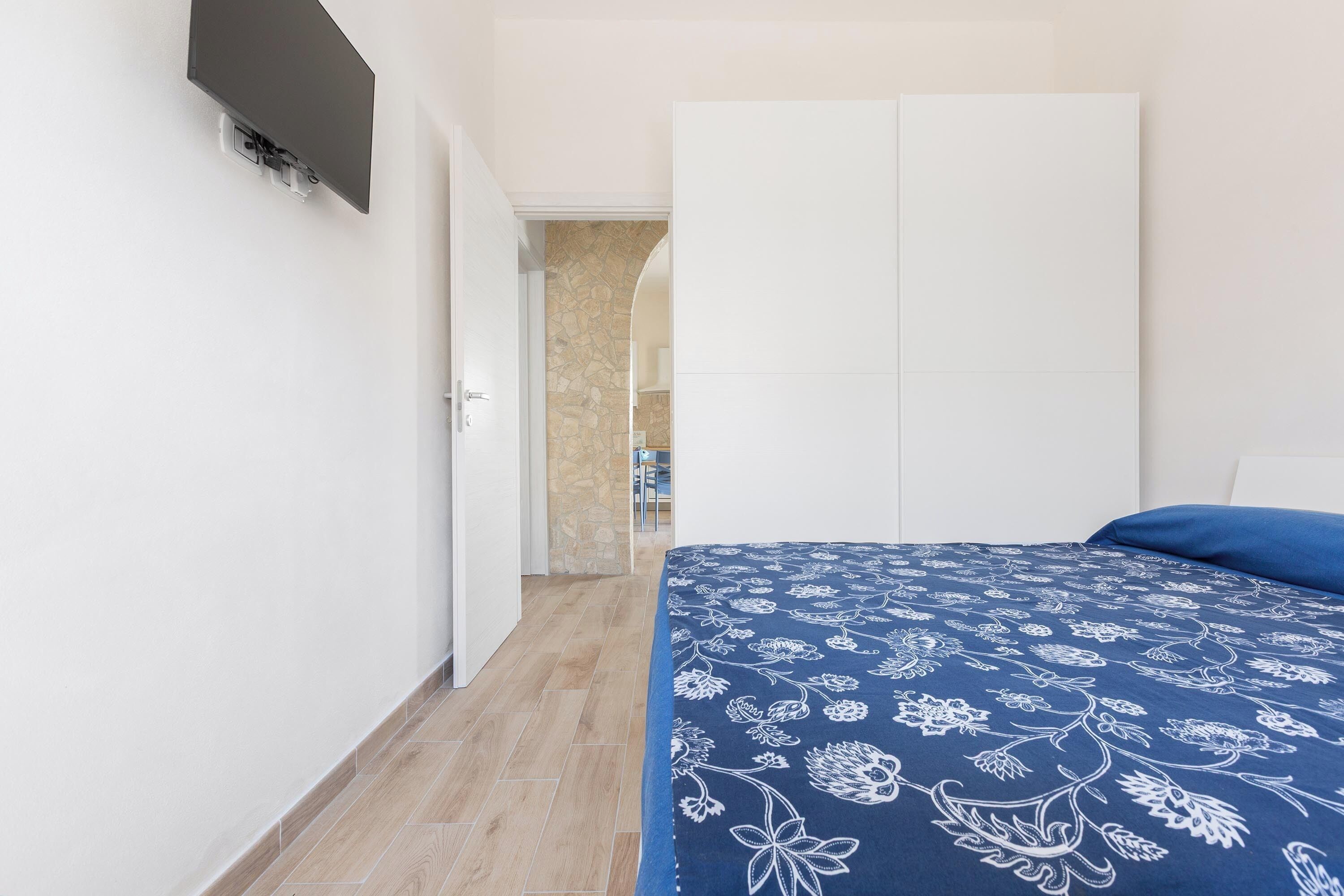 A bedroom with a bed, a wardrobe, and a door leading to another room.