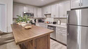 A modern kitchen with white cabinets, stainless steel appliances, and a wooden island.