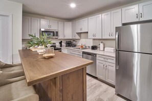 A modern kitchen with white cabinets, stainless steel appliances, and a wooden island. - The Ruby 104 (Pigeon Forge)