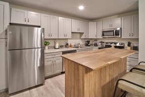 A modern kitchen with white cabinets, stainless steel appliances, and a wooden island. - The Ruby 105 (Pigeon Forge)