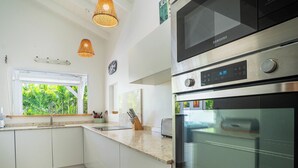 Eine moderne Küche mit weißen Schränken, einem Edelstahlbackofen und einem Fenster mit Blick auf Grünflächen.