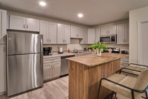 Une cuisine moderne dotée d’appareils électroménagers en acier inoxydable, d’un îlot central en bois et d’un coin repas.