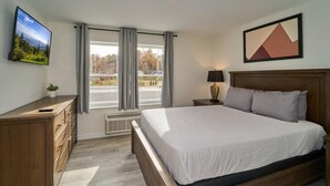 Ein Schlafzimmer mit einem Bett, einem Schminktisch, einer Lampe und einem Bild an der Wand.
