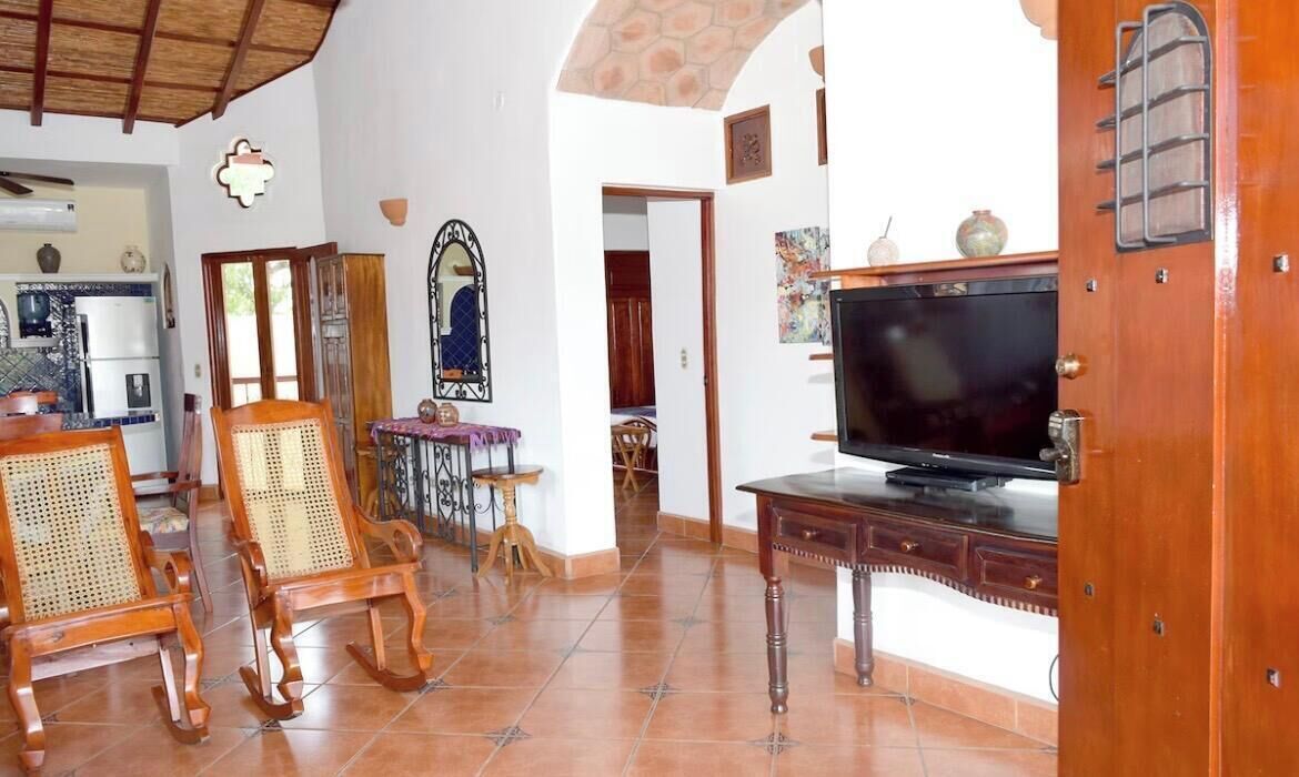 A living room with a television, wooden furniture, and a tiled floor.