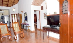 Una sala de estar con televisor, muebles de madera y piso de baldosas.