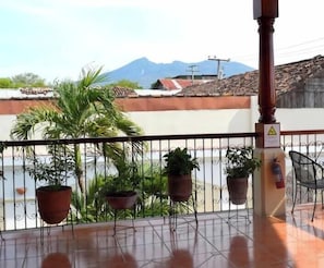 Un balcon avec des plantes en pot, une chaise et un extincteur.