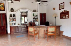 Une cuisine dotée d’un îlot central, de chaises en bois, d’un ventilateur de plafond et d’un sol carrelé.