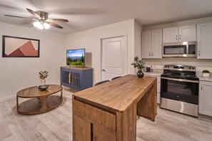 A modern kitchen with a wooden island, stainless steel appliances, and a ceiling fan. - The Ruby 108 (Pigeon Forge)