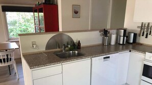 A modern kitchen with white cabinetry, a granite countertop, a stainless steel sink, and a dishwasher. - 4 Star Holiday Home in Esbjerg V (Esbjerg)