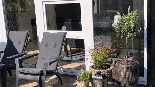 A patio with two chairs, a potted plant, and a lantern. - 4 Star Holiday Home in Esbjerg V (Esbjerg)